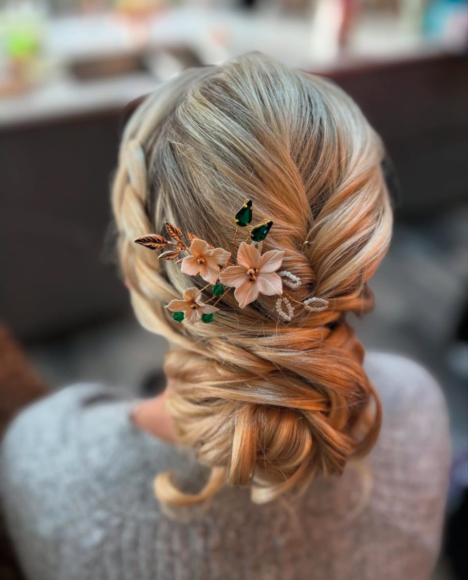 Elegant braided hairstyle adorned with delicate flowers and green leaves.