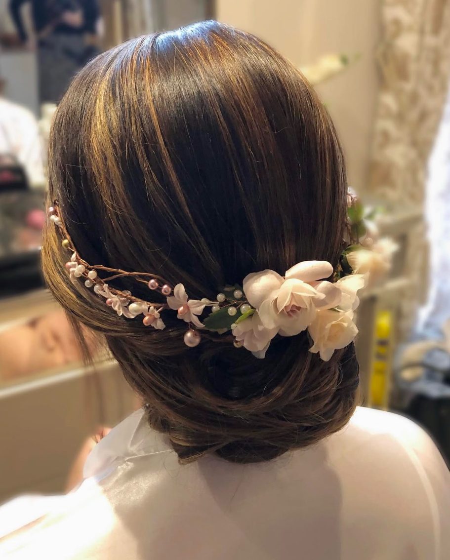 Elegant hairstyle adorned with flowers and decorative elements at the back. Redditch bridal hair and makeup artist 
