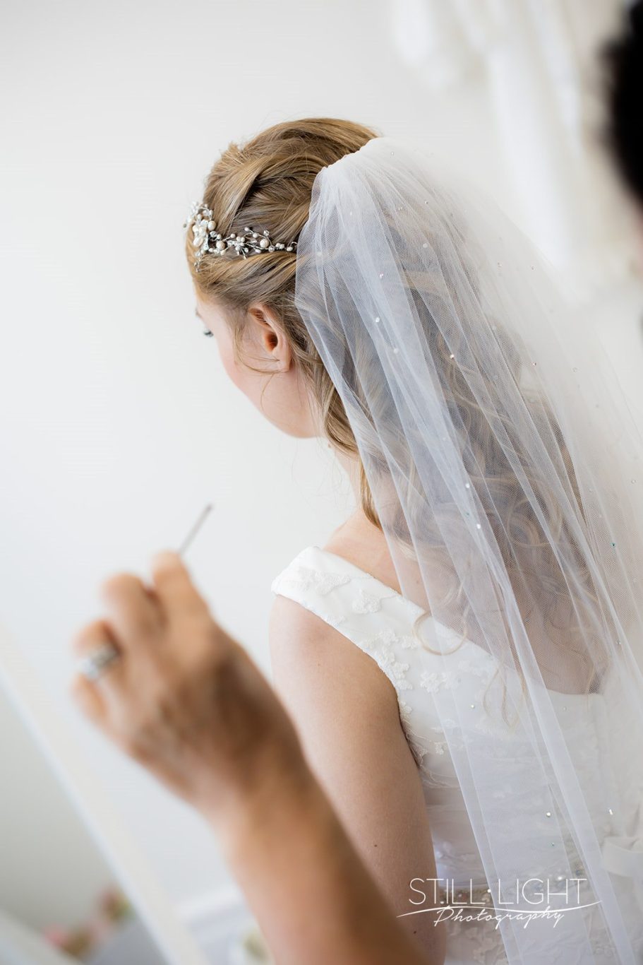 Bride in a white dress with a veil, preparing for her wedding.