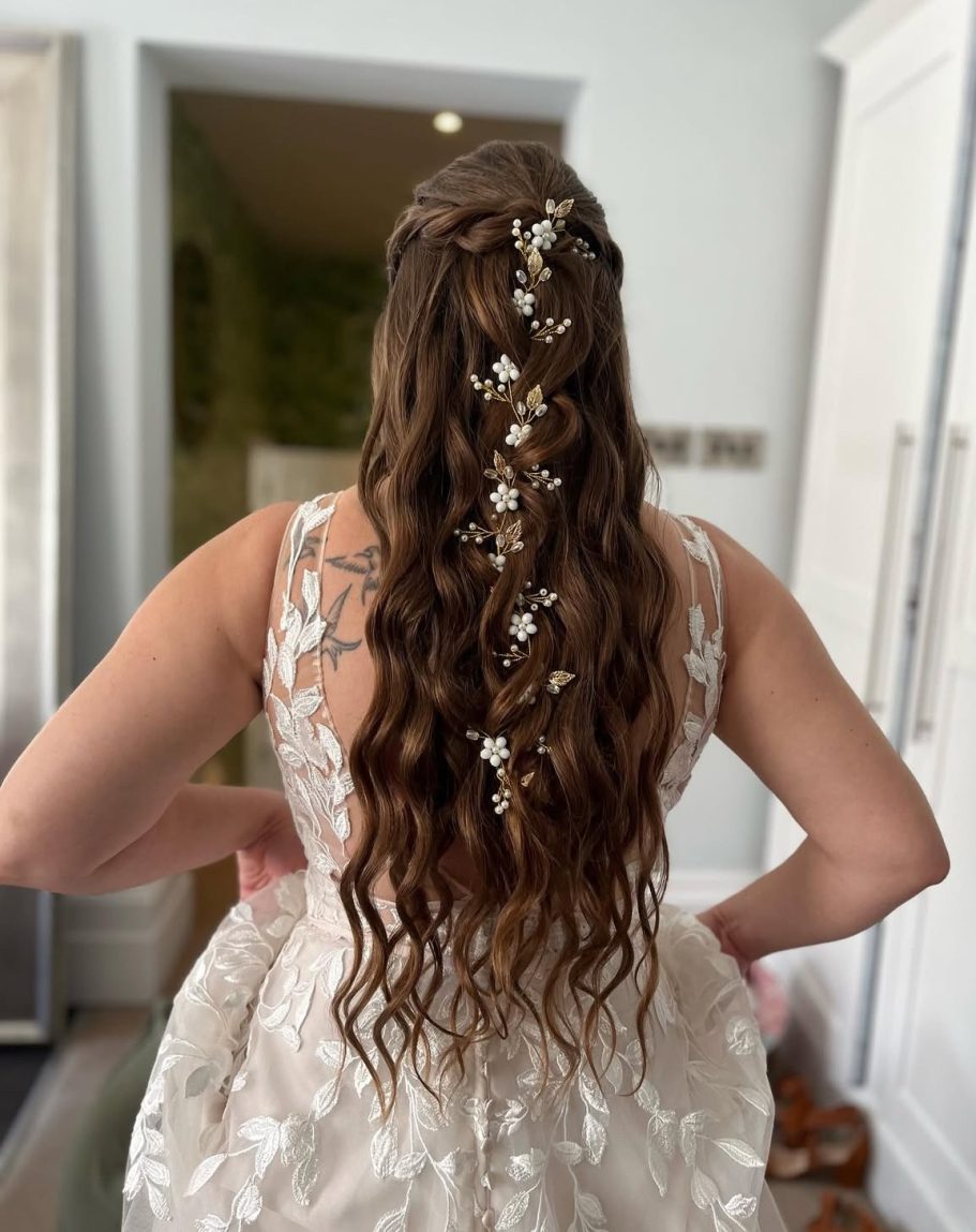 Woman with long, wavy hair adorned with white flowers, wearing a lace wedding gown.Bridal Hair with waves and sparkly hair vine.